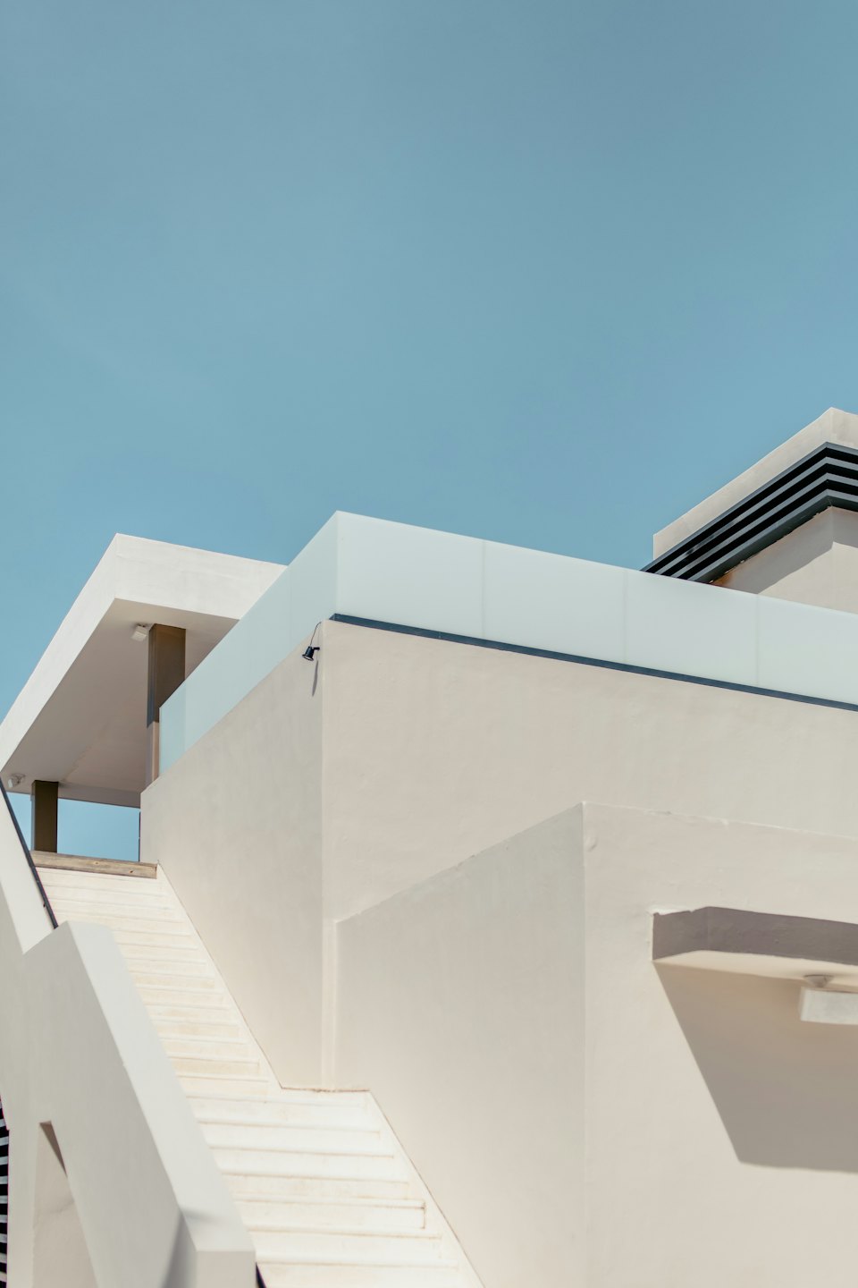 Modern beige building with white stairs and glass railings.