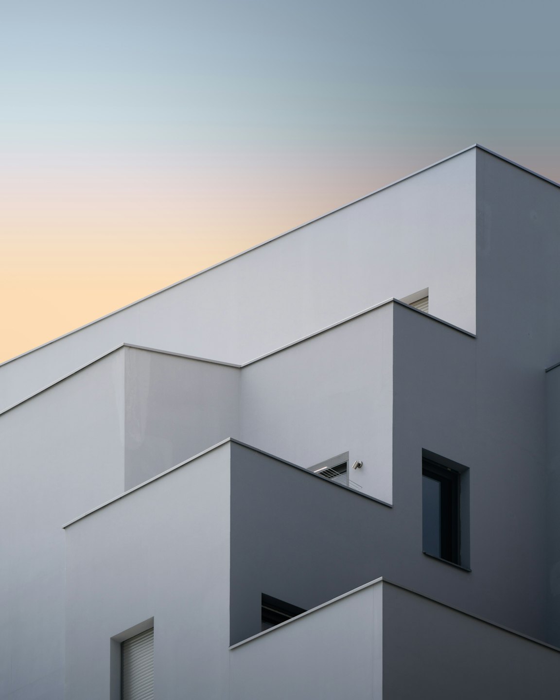A modern building with grey geometric walls and dark windows.