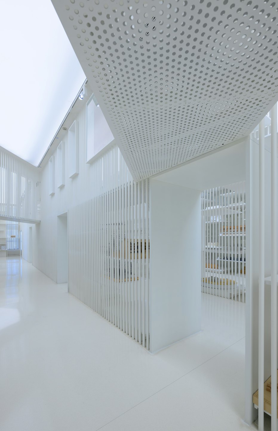 Modern architectural space with white slatted partitions and bright ceiling lights.