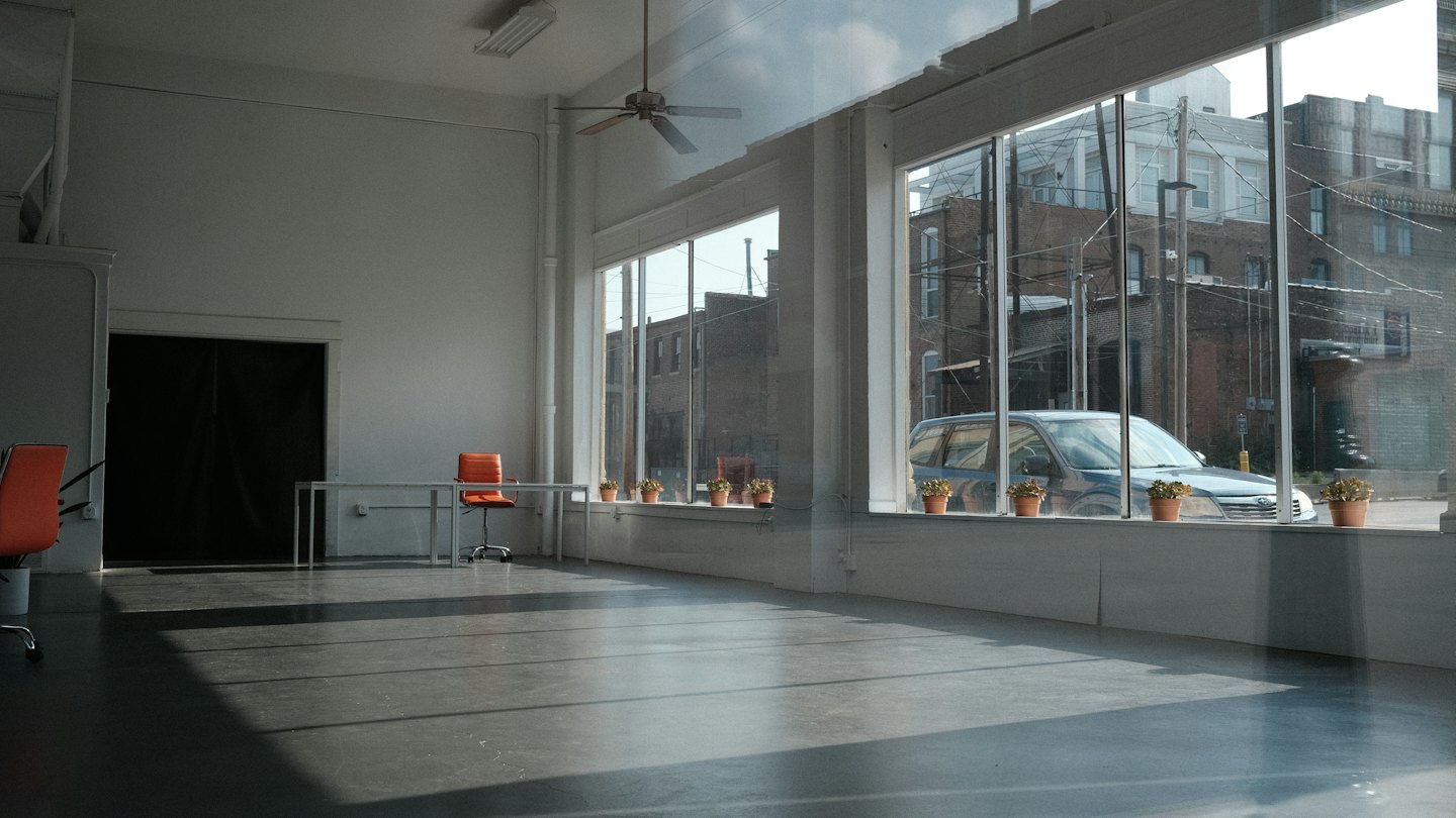Minimalist studio space with concrete floor and orange chairs.
